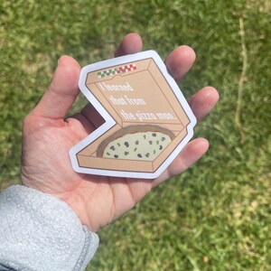 Puede incluir: Una pegatina de una caja de pizza con el texto "Eso lo aprend&iacute; del repartidor de pizza." en su interior. La caja de pizza es marr&oacute;n con detalles en cuadros rojos y blancos. La pizza dentro de la caja es verde y tiene aceitunas negras encima.