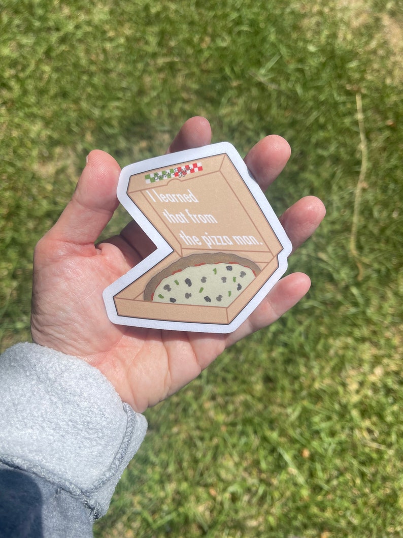 Puede incluir: Una pegatina de una caja de pizza con el texto "Eso lo aprend&iacute; del repartidor de pizza." en su interior. La caja de pizza es marr&oacute;n con detalles en cuadros rojos y blancos. La pizza dentro de la caja es verde y tiene aceitunas negras encima.