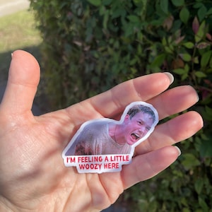 May include: A white sticker with a picture of a man with a shocked expression. The sticker has red text that says "I'm feeling a little woozy here."