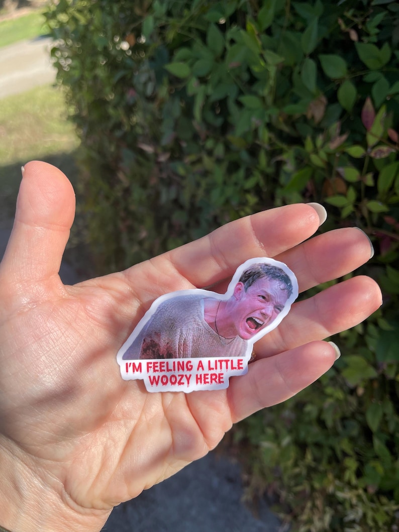 May include: A white sticker with a picture of a man with a shocked expression. The sticker has red text that says "I'm feeling a little woozy here."