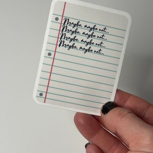 May include: A white sticker with a blue and green lined background and red lines. The sticker has black text that reads "Maybe, maybe not..." repeated four times.