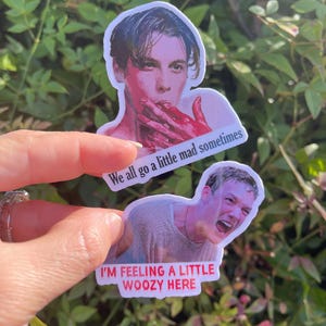 May include: Two stickers featuring images of actors from the movie "American Psycho". The top sticker features a close-up of Patrick Bateman with blood on his hands and the text "We all go a little mad sometimes". The bottom sticker features a close-up of Paul Allen with a distressed expression and the text "I'm feeling a little woozy here".