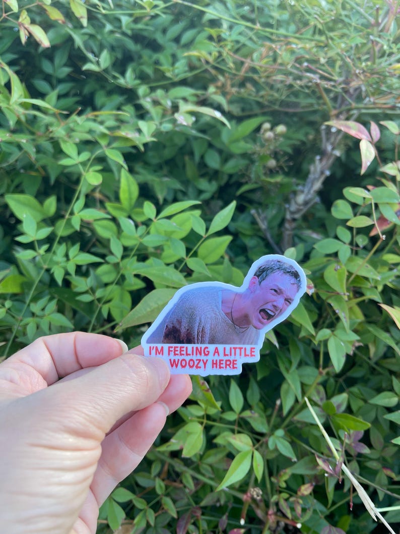 May include: A sticker featuring a man from a movie with a distressed expression, with the text "I'm feeling a little woozy here" in red.
