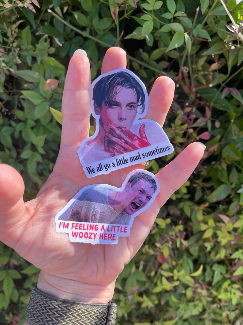 May include: Two stickers featuring images of actors from the movie "The Cabin in the Woods." The first sticker shows a man with blood on his face and the text "We all go a little mad sometimes." The second sticker shows a man with a shocked expression and the text "I'm feeling a little woozy here."
