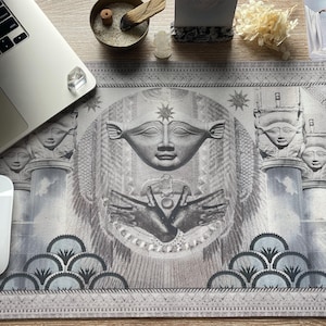 Puede incluir: Una alfombrilla de escritorio gris y blanca con un diseño que presenta una imagen estilizada de una mujer con alas, las manos extendidas y una estrella sobre su cabeza. El diseño también incluye patrones geométricos y un patrón repetitivo de olas estilizadas.
