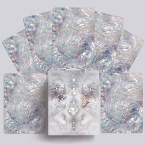 May include: A tarot deck with a central card depicting two figures and a pearl-adorned object. The cards have a pearlescent, swirling design in blue, white, and purple. The text "NA SAINT LE VIE" is visible on the central card.