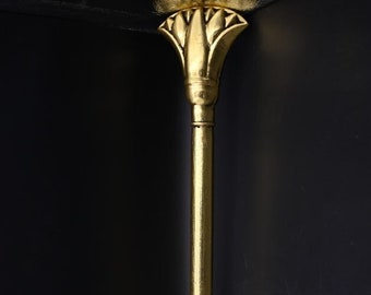 Puede incluir: Un bastón decorativo dorado con un diseño de flor de loto en la parte superior y un tenedor de dos puntas en la parte inferior.