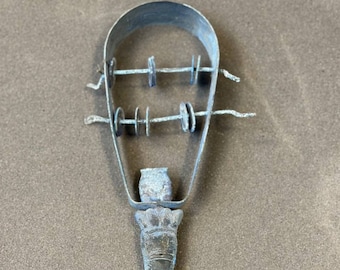May include: A vintage metal musical instrument with a handle and a series of metal rings that make a rattling sound when shaken.