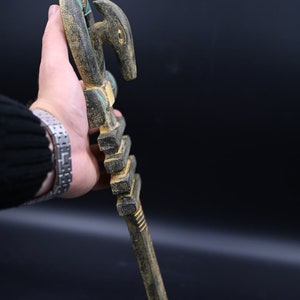 Puede incluir: Un bast&oacute;n de madera con una cabeza de animal tallada en la parte superior. El bast&oacute;n est&aacute; pintado en tonos de marr&oacute;n, negro y verde.