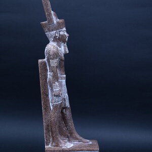 Puede incluir: Una estatua de piedra marr&oacute;n de un fara&oacute;n egipcio de pie sobre una base con jerogl&iacute;ficos. El fara&oacute;n lleva un alto tocado y una falda.