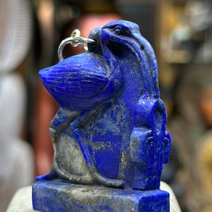 May include: A blue lapis lazuli pendant carved in the shape of a bird with a silver loop for hanging.