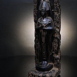 Puede incluir: Estatua de piedra negra de un fara&oacute;n egipcio con jerogl&iacute;ficos tallados en la piedra. El fara&oacute;n lleva un alto tocado y una larga t&uacute;nica.