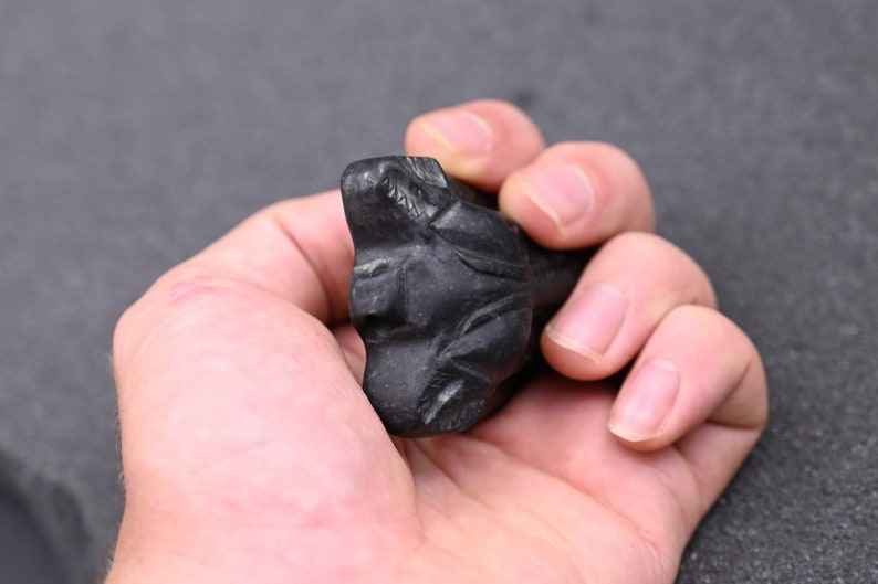 May include: A black carved stone sculpture of a wolf's head.