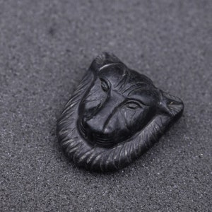 May include: A black carved stone pendant in the shape of a wolf's head.