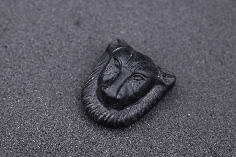 May include: A black carved stone pendant in the shape of a wolf's head.