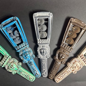 May include: Five wooden handheld musical instruments with a carved face and a row of metal discs inside. The instruments are painted in shades of blue, green, brown, and white.