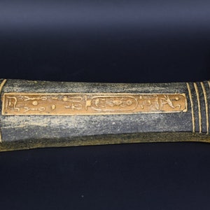 Puede incluir: Una daga decorativa negra y dorada con jerogl&iacute;ficos en el mango.