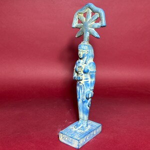 May include: Blue ceramic statue of an Egyptian goddess with a crown and holding a staff. The base of the statue has hieroglyphics.