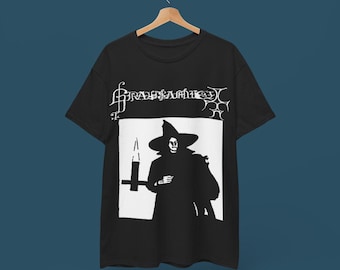 May include: Black t-shirt with a white graphic of a person in a witch's hat and robe, holding a candle. The text "GRAVITY'S RAIN" is printed above the graphic.