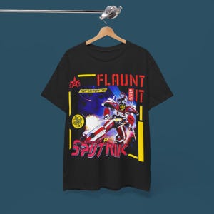 May include: Black t-shirt with a graphic print of a robot in a futuristic setting. The text "FLAUNT IT" is printed in red and yellow on the shirt. The robot is red, white, and blue with a yellow star on its chest. The text "A 21st CENTURY TOY" is printed in white below the robot.