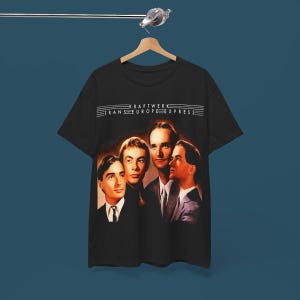 Op de afbeelding: Zwart T-shirt met een afbeelding van de band Kraftwerk. De afbeelding toont de bandleden en de tekst "Kraftwerk Trans-Europe Express".
