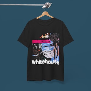 May include: Black t-shirt with a vibrant graphic design. The design includes figures, a pink structure, and the word "whitehouse" in white block letters. The design has a collage aesthetic.
