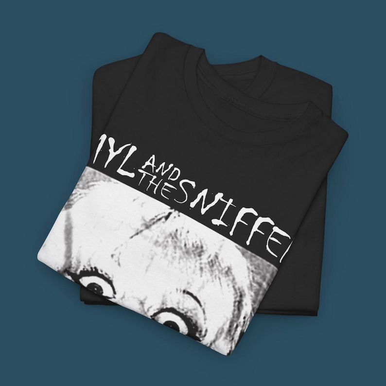 May include: Black t-shirt with white text that reads "And The Sniffers" with a black and white image of a person's face with large eyes.