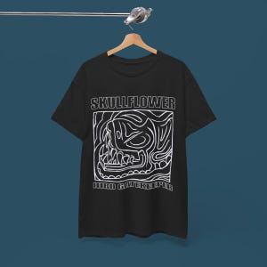 May include: A white ceramic mug with a black handle and the text "But First, Coffee" in a bold, black font. The mug is set against a blurred background, suggesting a cozy setting.