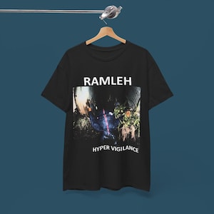May include: Black t-shirt with the word "RAMLEH" in white block letters above a photo. The photo shows a dark, blurry scene with the words "HYPER VIGILANCE" in white block letters below the photo.
