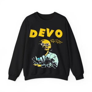 Op de afbeelding: Zwart sweatshirt met een gele afbeelding van een persoon met een bril en het woord "DEVO" in gele letters. De tekst "we're all de-vo! boogie boy xo" is in gele cursieve letters onder de afbeelding geschreven.