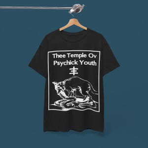 Puede incluir: Camiseta negra con un estampado gráfico blanco de un lobo atacando a una serpiente. El texto "Thee Temple Ov Psychick Youth" y un símbolo están impresos sobre el gráfico.
