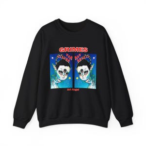 May include: Black sweatshirt featuring a graphic of two alien-like figures with three eyes, set against a blue starry background. The word "GRIMES" is arched above the image, with "Art Angel" below.