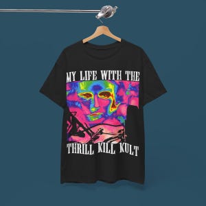 Puede incluir: Camiseta negra con un estampado gráfico de un rostro en un esquema de colores arcoíris. El texto "My Life With The Thrill Kill Kult" está impreso en blanco debajo de la imagen.