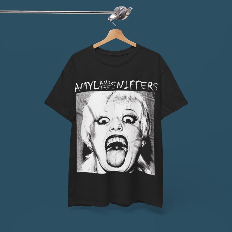 May include: Black t-shirt with a white graphic of Amyl and the Sniffers band name and a black and white photo of a woman with her tongue sticking out.