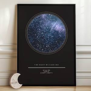 May include: A black framed vertical poster featuring a circular star map with constellations in shades of blue and purple. Below the map, the text reads THE NIGHT WE SAID I DO, 14th June 2035, Bradbourne, 52.73885° N, 1.62808° W. A small crescent moon object sits nearby.
