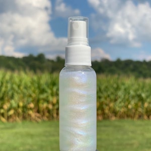 May include: A clear plastic bottle with a white spray nozzle filled with iridescent white glitter liquid.