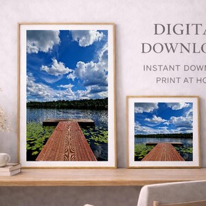 May include: Two framed landscape prints of a lake scene with a wooden dock extending into the water under a blue sky with fluffy white clouds. The text "DIGITAL DOWNLOAD" and "PRINT AT HOME" is visible.