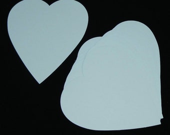 May include: A stack of light blue heart-shaped paper cutouts, with one heart separated from the stack. The hearts are a solid color and are displayed against a black background. The paper has a smooth texture.