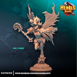 May include: A miniature figurine of a fairy with wings, a flower crown, and a staff. The fairy is standing on a base with flowers and leaves. The figurine is painted in a light brown colour. The text "FAY / FAIRY" is visible below the figurine.