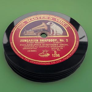 Könnte beinhalten: Ein Stapel schwarzer Vinyl-Schallplatten mit einem roten runden Etikett. Das Etikett enthält den Text His Master's Voice, Hungarian Rhapsody No. 2, Philadelphia Symphony Orchestra und Leopold Stokowski sowie eine Abbildung eines Hundes.