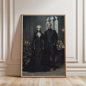 May include: A framed print featuring a man and woman in gothic attire. The woman wears a black gown with lace details, while the man is in a black suit and coat. The background shows a dimly lit room with candles and a stained-glass window.