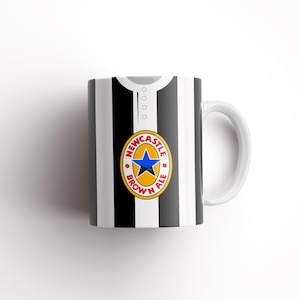 May include: White ceramic mug with a black and white striped design. The mug has a Newcastle Brown Ale logo on the front.