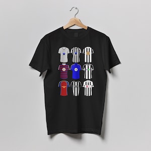 May include: Black t-shirt featuring a collection of soccer jerseys. The jerseys are in various colors, including blue, red, white, and black, with different patterns and designs. The shirt is hanging on a wooden hanger.