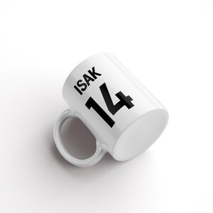 May include: White ceramic mug with black text that reads "ISAK 14".