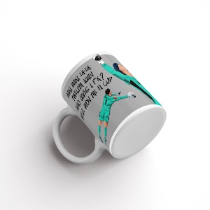 May include: White ceramic mug with a wraparound design featuring a soccer player in a teal uniform. The mug has text that reads, "Why win it again, twelfth again, who gives a f*ck? We won the FA Cup."