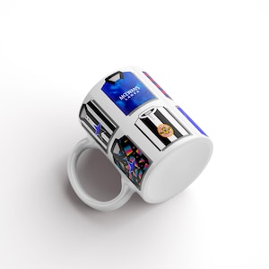 Peut inclure: Une tasse en c&eacute;ramique blanche avec un motif de diff&eacute;rents maillots de football, dont un maillot bleu avec le texte "McEwans Lager" dessus.