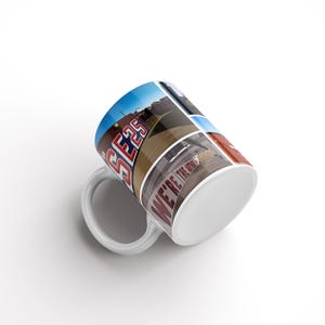 May include: White ceramic mug with a collage of photos printed on the side. The photos feature a red sign that says "SE25", a blue sign that says "WE'RE THE HOME", and other cityscapes.