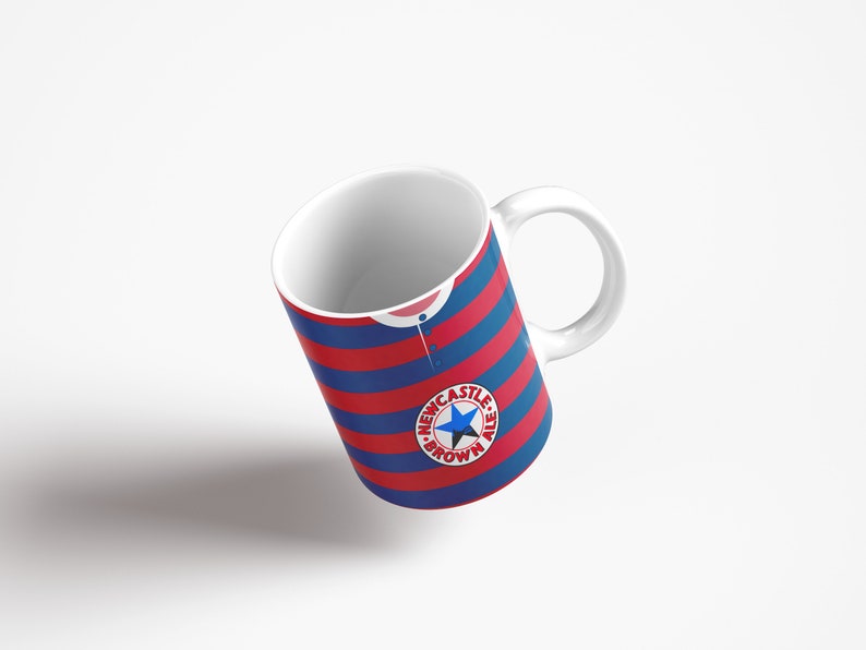 May include: White ceramic mug with a blue and red striped design. The mug features a circular logo with a star and the text "Newcastle Brown Ale".