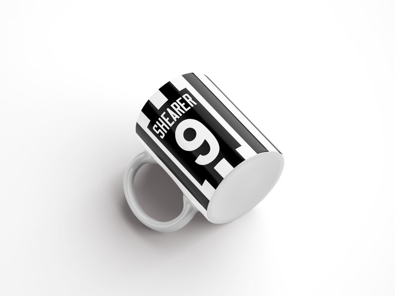 May include: White ceramic mug with a black and white striped design. The mug has the text "SHEARER 9" printed on it.