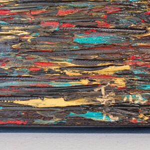 K&ouml;nnte beinhalten: Nahaufnahme eines strukturierten, mehrfarbigen Gem&auml;ldes mit horizontalen Pinselstrichen in Rot-, Blau-, Gold- und Schwarzt&ouml;nen. Das Gem&auml;lde hat eine raue, geschichtete Textur und scheint auf einer Holzoberfl&auml;che zu sein.